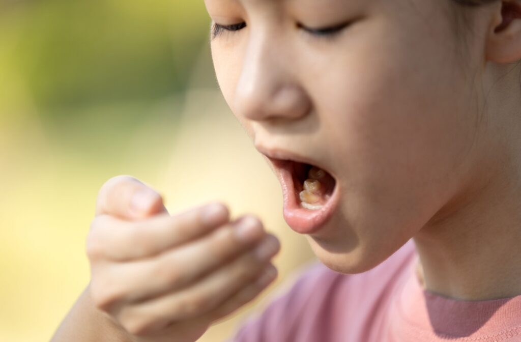 A child holding their hand near their mouth, appearing to check for bad breath or odor.